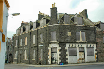 Picture of the front of a dilapidated building, the former Islay Hotel in Port Ellen