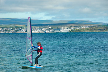 Picture of a windsurfer on a sea loch, the village of Bowmore in the background