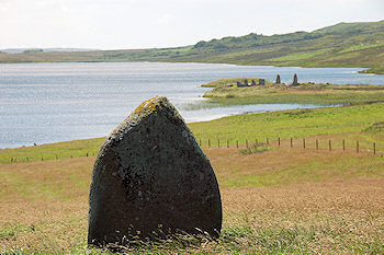 Picture of a standing stone with an island in a loch in the background