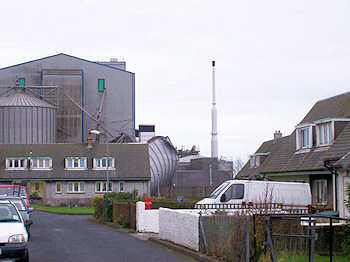 Picture of a road with house before an industrial maltings with a collapsed silo