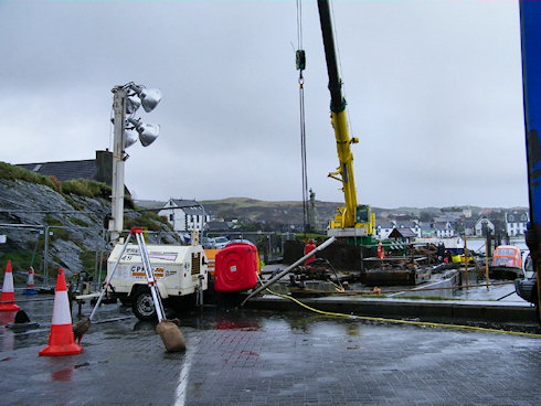 Picture of a crane at pier repair work, some big lamps on the left