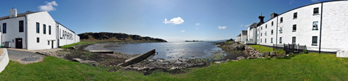 Picture of a panoramic view of a small sea loch, flanked by a distillery