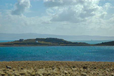 Picture of houses on a peninsula, a lighthouse in the distance behind it