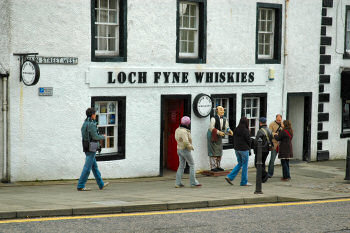 Picture of the front of a whitewashed building with the sign Loch Fyne Whiskies, pedestrians in front