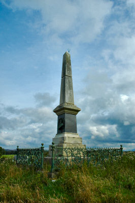 Picture of a monument / obelisk for John Francis Campbell on Islay, surrounded by a fence