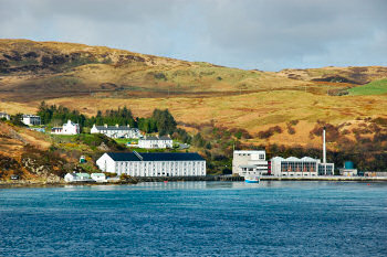 Picture of the whitewashed buildings of a distillery near the shore (Caol Ila on Islay)