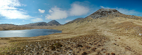 Picture of a panoramic view over a loch (lake) and three mountains, the Paps of Jura
