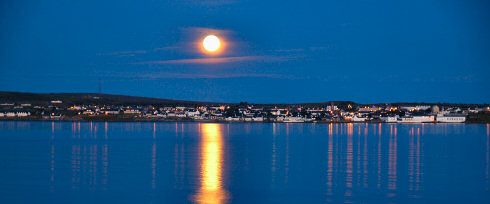 Picture of the moon rising over a coastal village