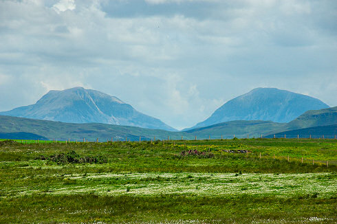 Picture of two round shaped hills with a field full of cottongrass in the foreground