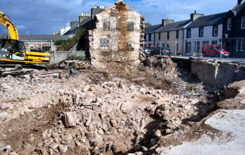 Picture of a hole in the ground with rubble where a building used to stand