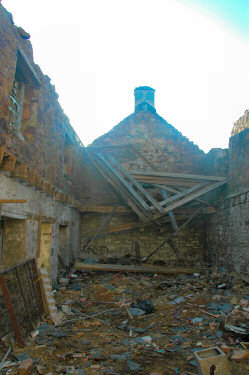 Picture of the inside of an old building, rubbish and debris on the ground, the roof collapsed