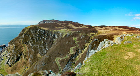 Picture of a panoramic view over some steep cliffs with some walkers on the top of the cliffs