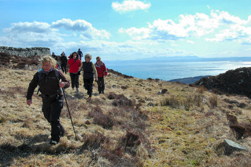 Picture of walkers on a hill with a sound and distant islands in the background