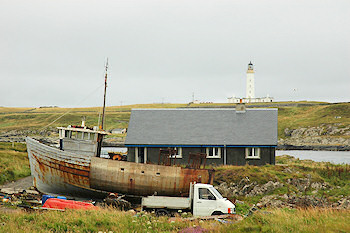 Picture of a trawler under repair in a boat yard, a lighthouse in the background