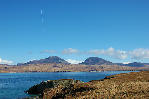 Picture of two round shaped mountains see over a sound, the Paps of Jura seen of the Sound of Islay