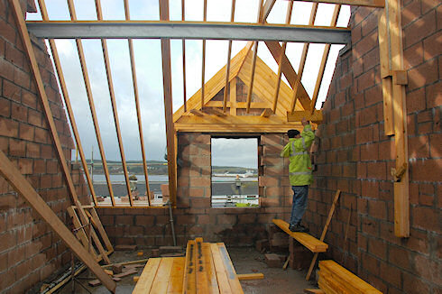 Picture of a carpenter working on a roof, seen from inside of a building
