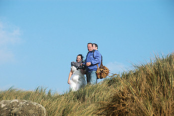 Picture of a photographer with a newly wed couple on the top of a dune