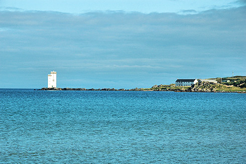 Picture of a calm bay with a lighthouse and house at the end