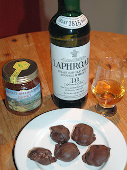 Picture of a plate with chocolate truffles, behind it a bottle of Laphroaig and a glass of honey