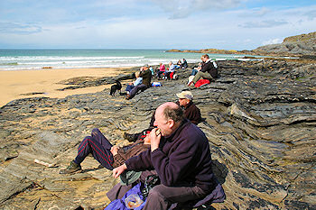 Picture of a group of walkers having a picnic on rocks overlooking a sandy beach