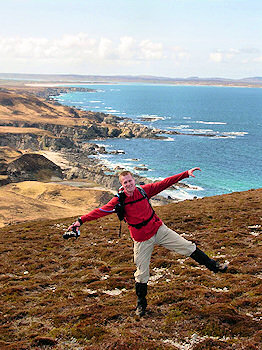 Picture of a man on the top of a hill with a shoreline behind