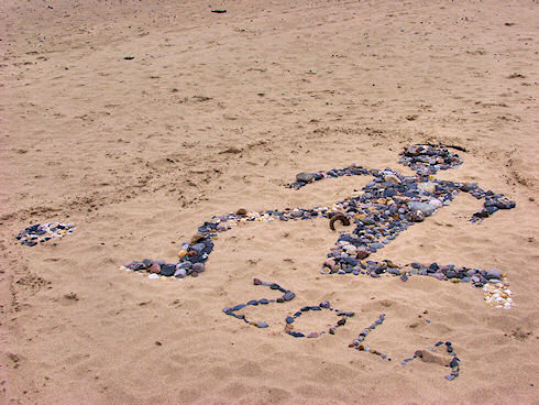 Picture of a mural in the sand of a beach made from stones and other finds on a beach
