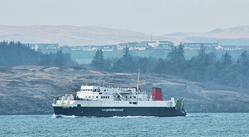 Picture of a ferry in a sound between two islands, a village in the background