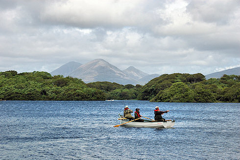 Picture of a boat with anglers on a loch, some distinctive mountains in the background