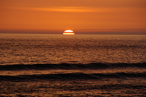 Picture of a sunset with the sun just disappearing behind the horizon