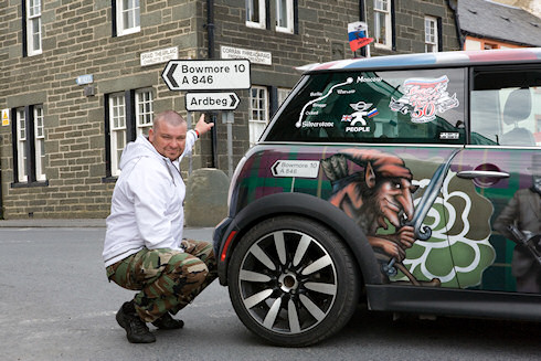 Picture of a nicely painted Russian Mini in front of the Bowmore sign in Port Ellen