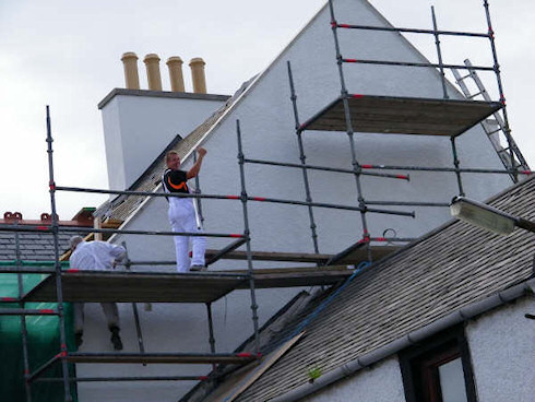 Picture of the gable end of a hotel under construction, workmen just finishing painting it