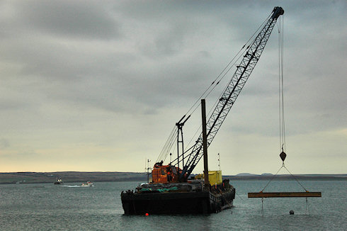 Picture of a barge with a crane, a coaster and a passing fishing boat