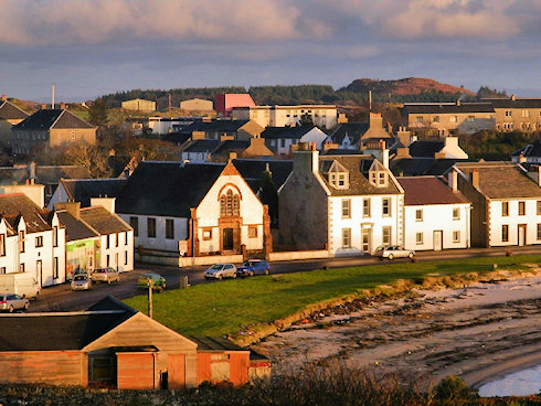 Picture of a village road along a bay, a church hall in the centre
