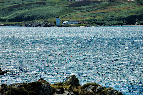 Picture of a lighthouse seen across the entrance to a wide bay