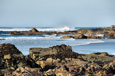 Picture of waves coming in on a rocky shore, spray being blown backwards