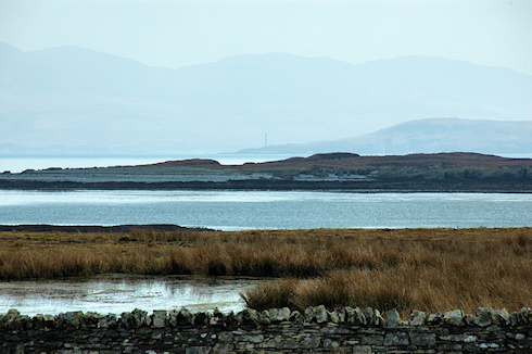 Picture of a view across a wide sound between three islands, the islands in the distance just visible through the haze