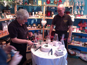 Picture of a woman cutting a cake with a silhouette of Islay, a man watching on