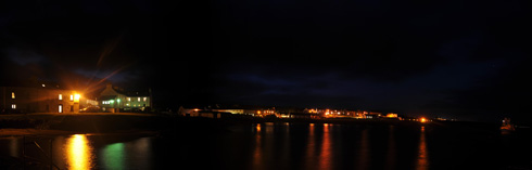 Picture of a panoramic view over a coastal village at night, shown in correct colours