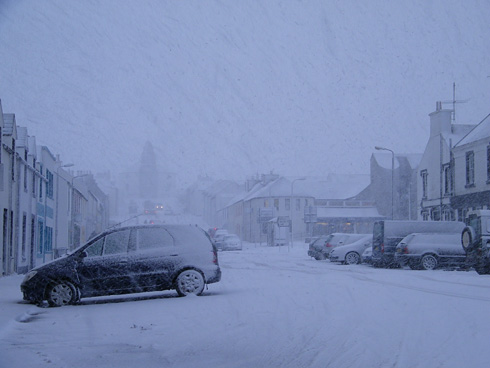 Picture of a heavy snowshower over a village main street (Bowmore, Islay)