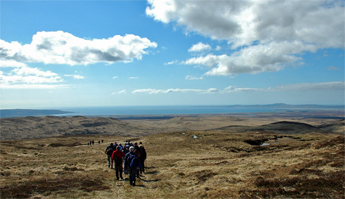 Picture of a group of walkers walking down a hill towards a wide bay
