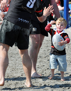 Picture of a young boy in rugby clothes holding a rugby ball while giving high five