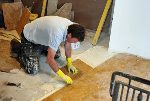 Picture of a man laying floor tiles