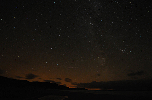 Picture of a night sky with millions of stars over a wide bay