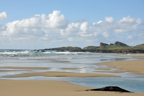 Picture of a beach on Islay with interestingly shaped cliffs in the distance