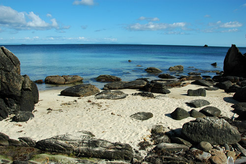 Picture of golden sandy beach with a few rocks
