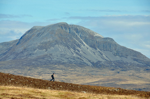 Picture of a walker on a low ridge with a large mountain behind
