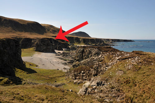 Picture of a coast with steep cliffs and raised beaches, an arrow pointing to a location