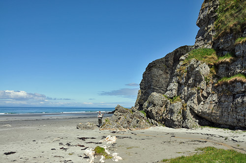 Picture of a woman on a beach under some high steep cliffs