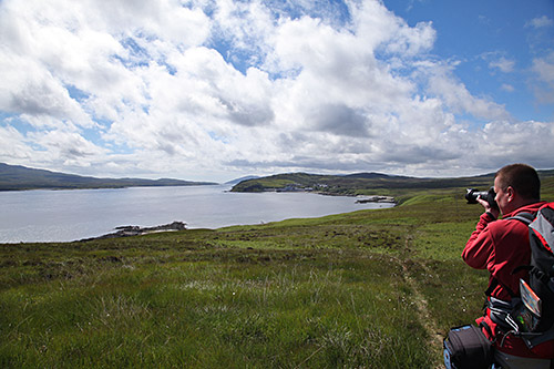 Picture of a man taking a picture of a distillery at a sound between two islands