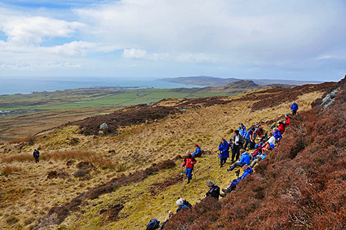 Picture of a group of walkers on a hillside high above a coastline